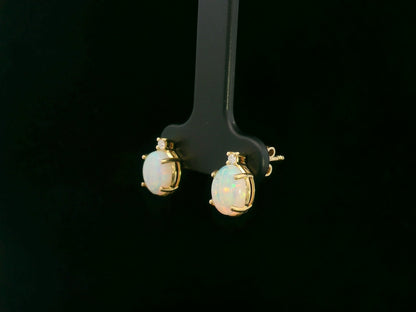 18K yellow gold opal and diamond stud earrings with oval opals and subtle diamond accents, luxury fine jewelry by Emirates Diamonds.