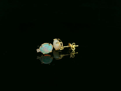 18K yellow gold opal and diamond stud earrings with oval opals and subtle diamond accents, luxury fine jewelry by Emirates Diamonds.