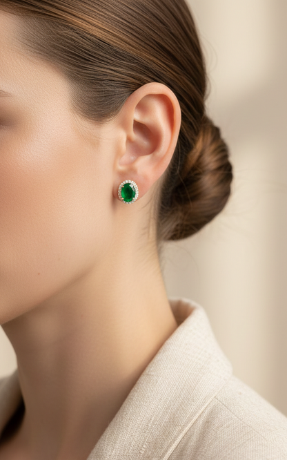 18K yellow gold emerald and diamond halo stud earrings with oval emeralds and brilliant diamond accents by Emirates Diamonds.