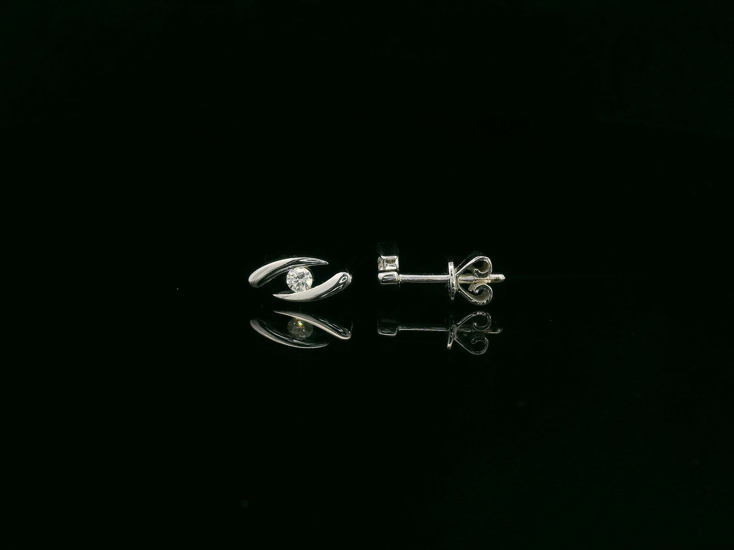 18K white gold modern diamond stud earrings with sculptural swirl design and round diamonds, total diamond weight 0.12 carat, Emirates Diamonds.