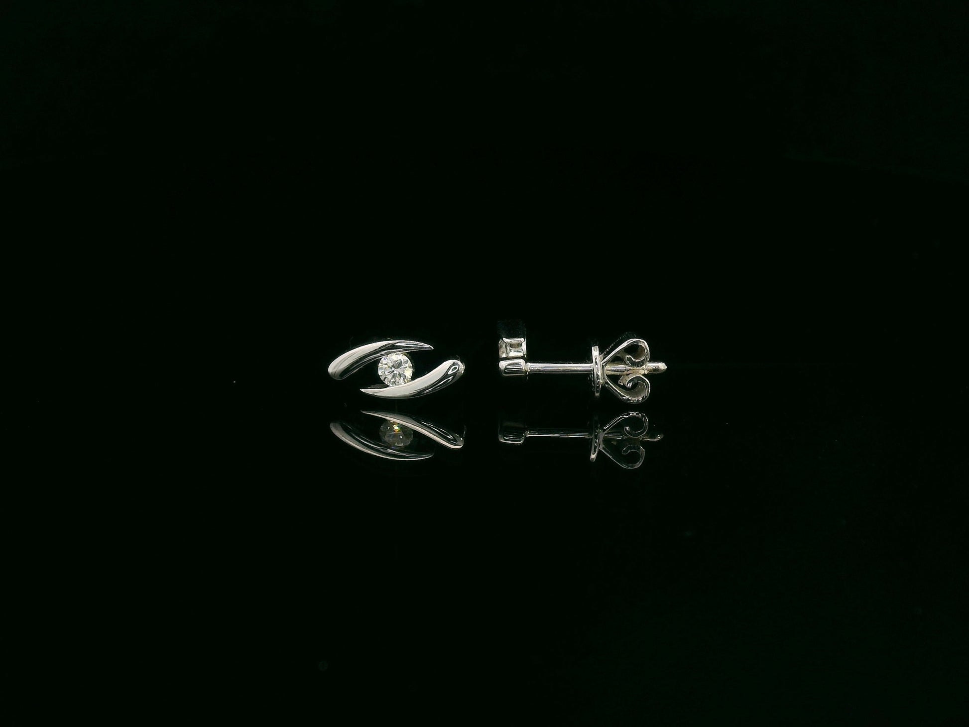 18K white gold modern diamond stud earrings with sculptural swirl design and round diamonds, total diamond weight 0.12 carat, Emirates Diamonds.