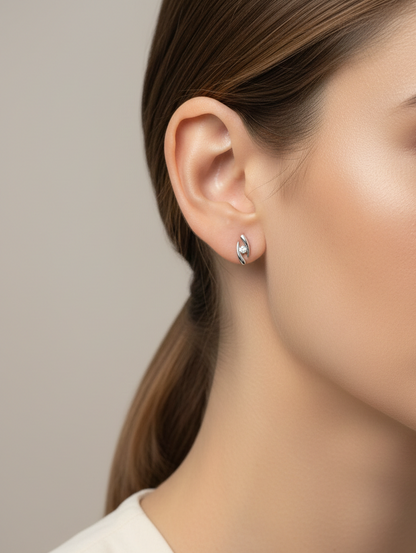 18K white gold modern diamond stud earrings with sculptural swirl design and round diamonds, total diamond weight 0.12 carat, Emirates Diamonds.