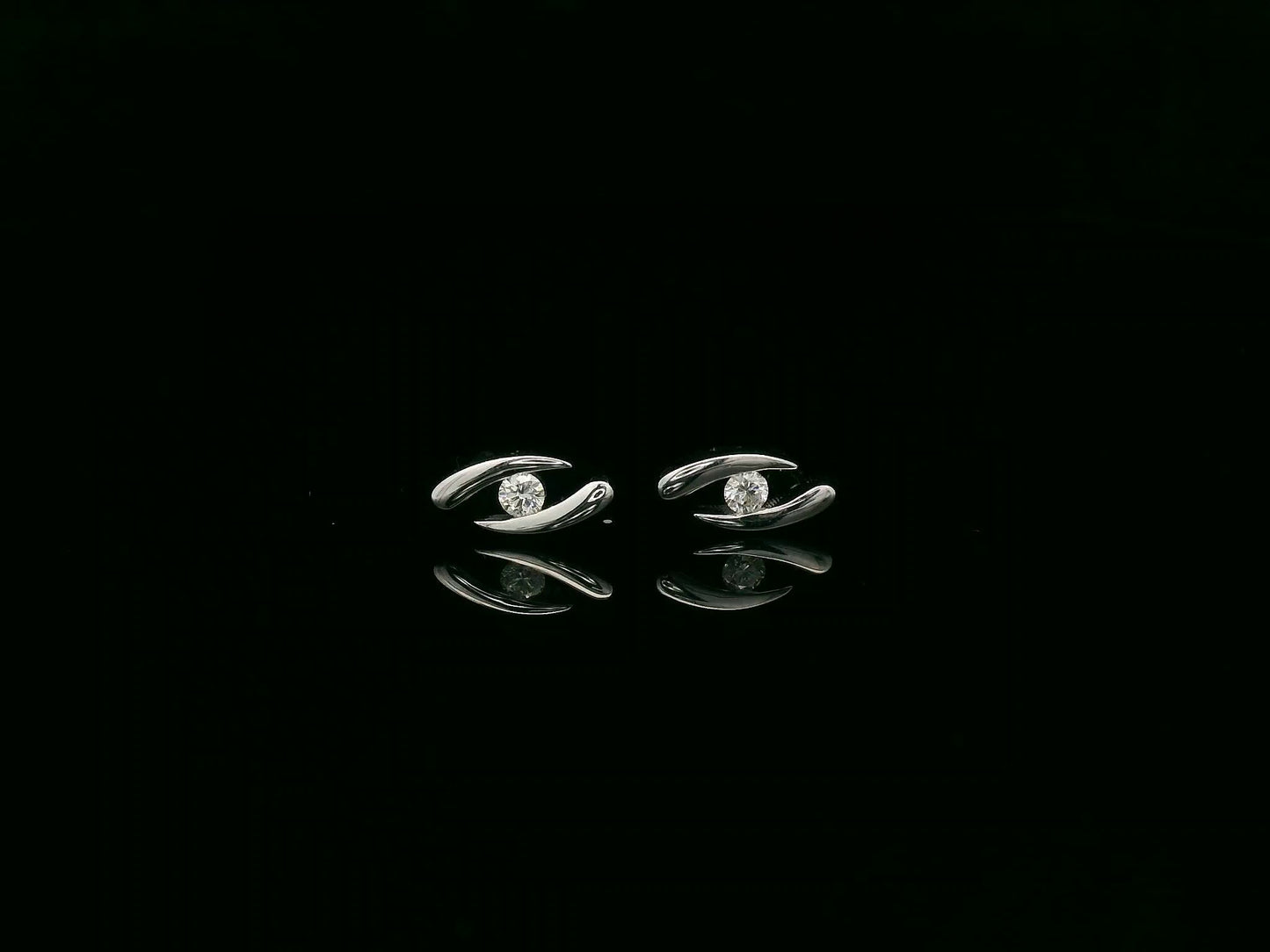 18K white gold modern diamond stud earrings with sculptural swirl design and round diamonds, total diamond weight 0.12 carat, Emirates Diamonds.