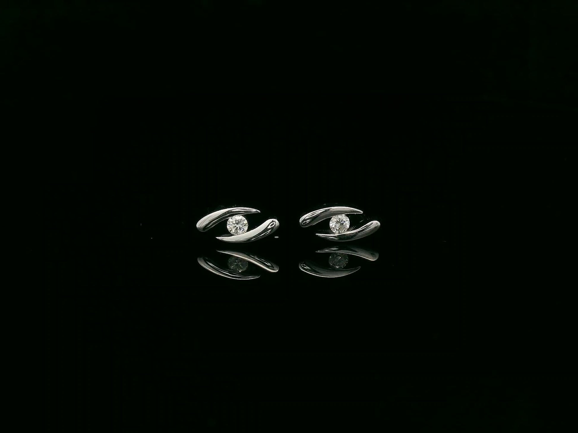 18K white gold modern diamond stud earrings with sculptural swirl design and round diamonds, total diamond weight 0.12 carat, Emirates Diamonds.