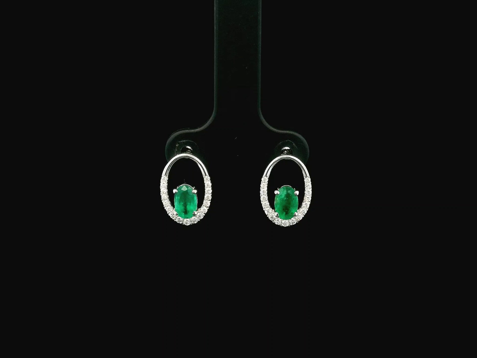 Emerald and diamond halo stud earrings in 18K white gold featuring 0.92 carat emeralds and 0.20 carat diamonds by Emirates Diamonds.