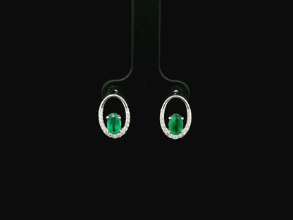 Emerald and diamond halo stud earrings in 18K white gold featuring 0.92 carat emeralds and 0.20 carat diamonds by Emirates Diamonds.