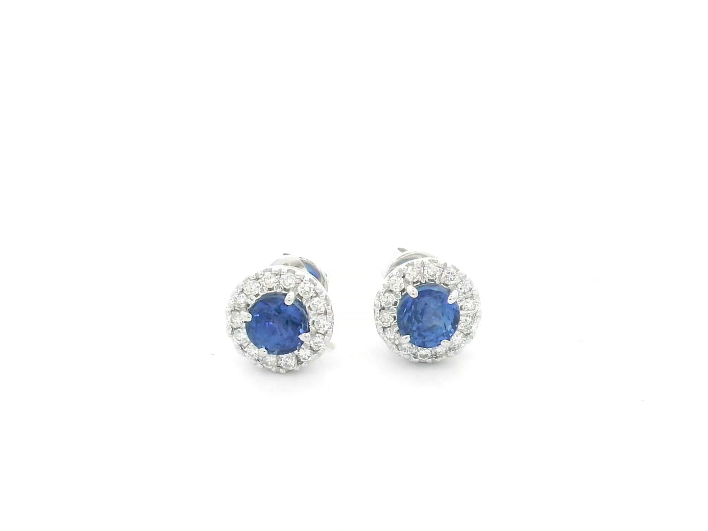 18K white gold sapphire halo stud earrings featuring 1.06 carats of blue sapphires surrounded by 0.16 carats of natural diamonds.