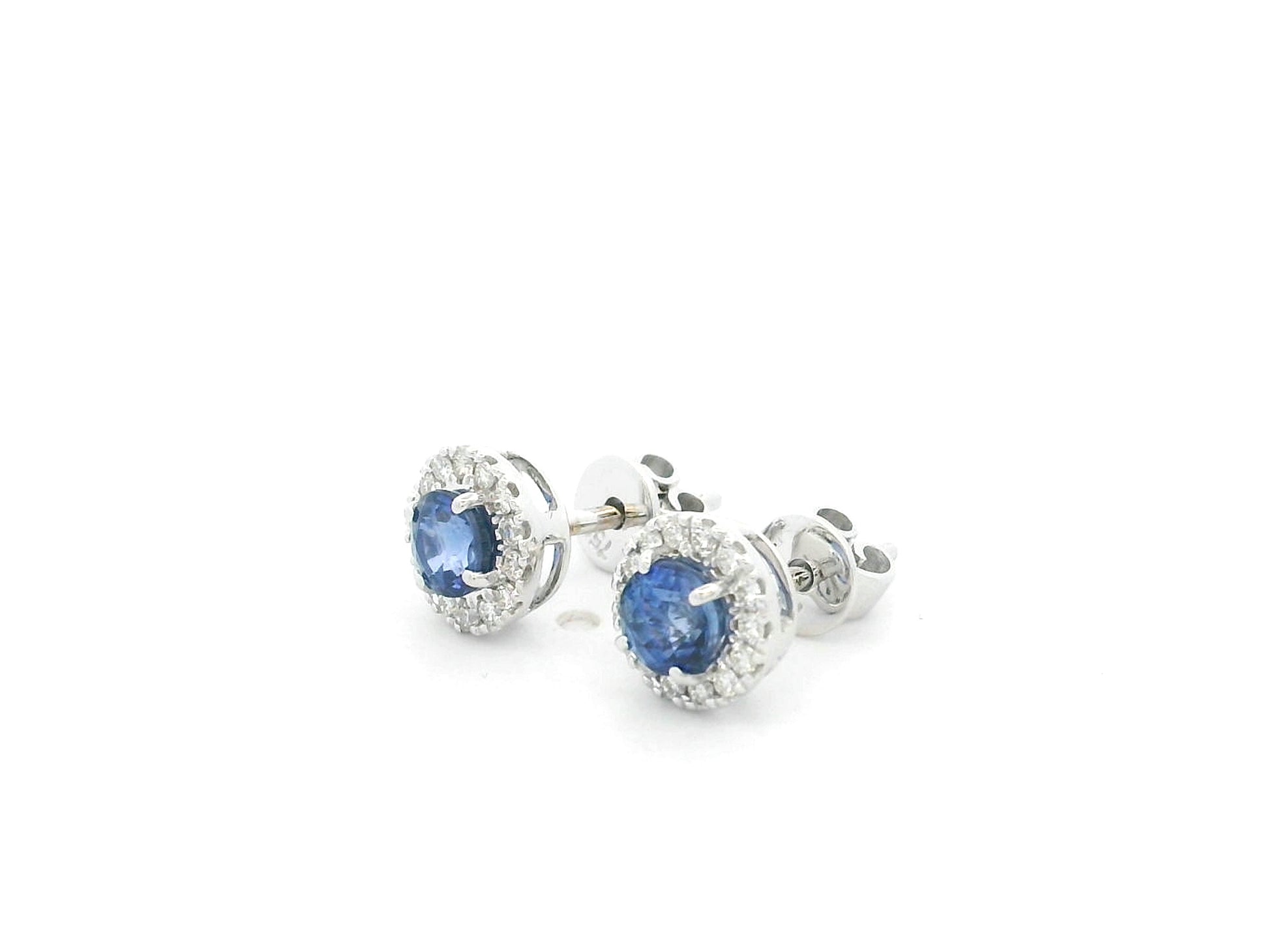 18K white gold sapphire halo stud earrings featuring 1.06 carats of blue sapphires surrounded by 0.16 carats of natural diamonds.