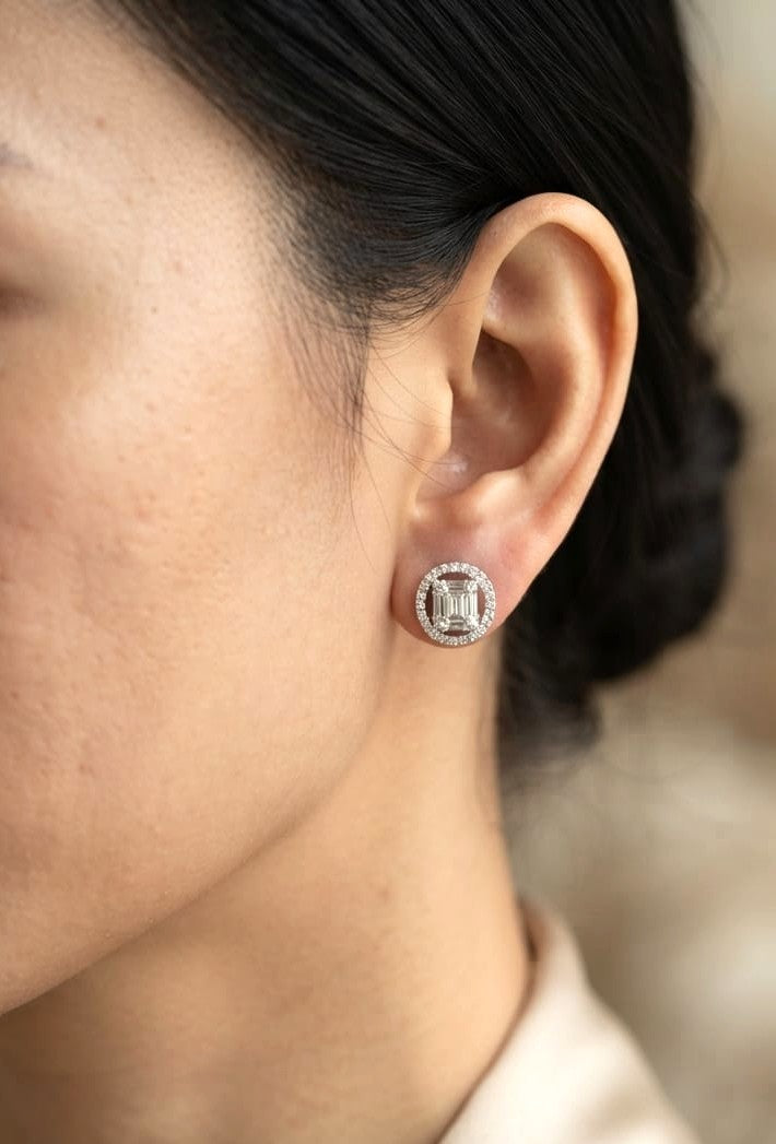 18K white gold emerald cut illusion diamond stud earrings featuring round and baguette natural diamonds with a sparkling round diamond halo and secure butterfly backs.
