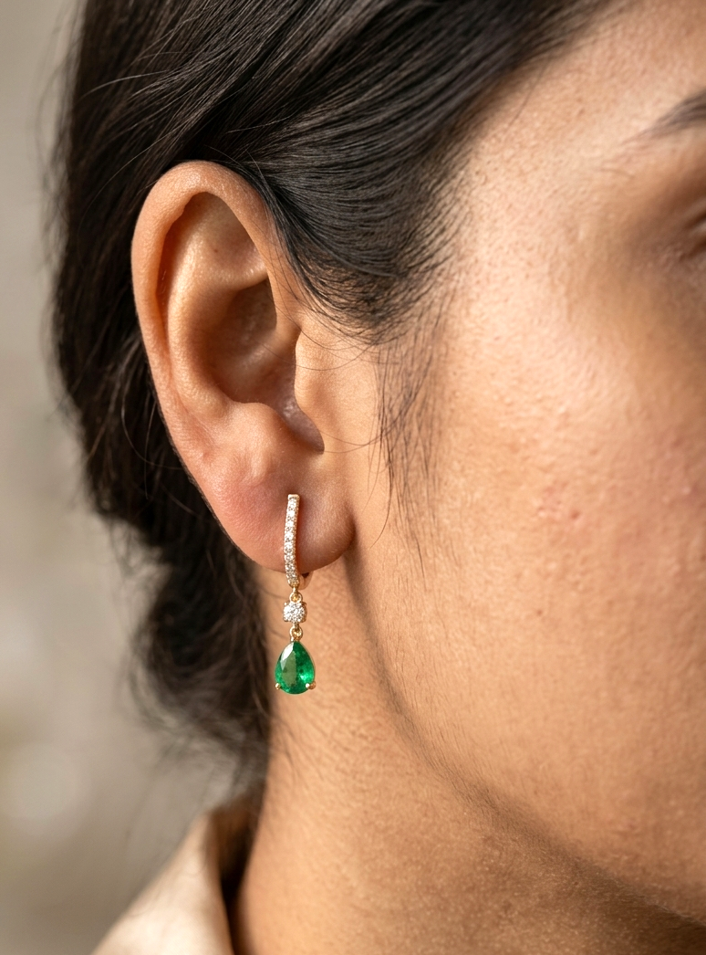 18K Yellow Gold Emerald Drop Earrings featuring 1.00 carat natural pear-shaped emeralds suspended from diamond huggie hoops with 0.31 carat natural diamonds.