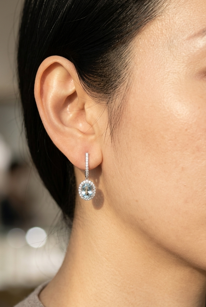 18K White Gold Aquamarine Drop Earrings featuring 1.50 carats of natural oval aquamarines surrounded by diamond halos with diamond huggie hoops and 0.48 carat natural diamonds.