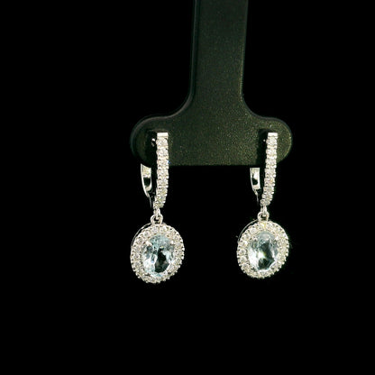 18K White Gold Aquamarine Drop Earrings featuring 1.50 carats of natural oval aquamarines surrounded by diamond halos with diamond huggie hoops and 0.48 carat natural diamonds.