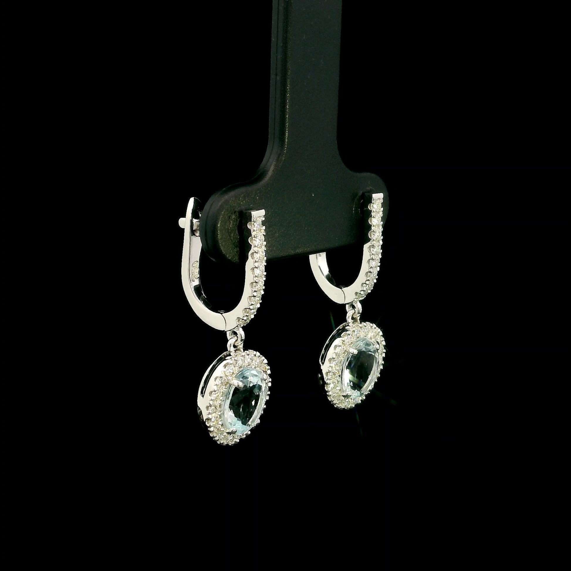 18K White Gold Aquamarine Drop Earrings featuring 1.50 carats of natural oval aquamarines surrounded by diamond halos with diamond huggie hoops and 0.48 carat natural diamonds.