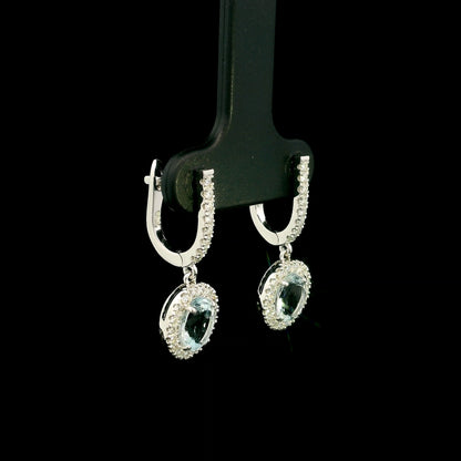 18K White Gold Aquamarine Drop Earrings featuring 1.50 carats of natural oval aquamarines surrounded by diamond halos with diamond huggie hoops and 0.48 carat natural diamonds.