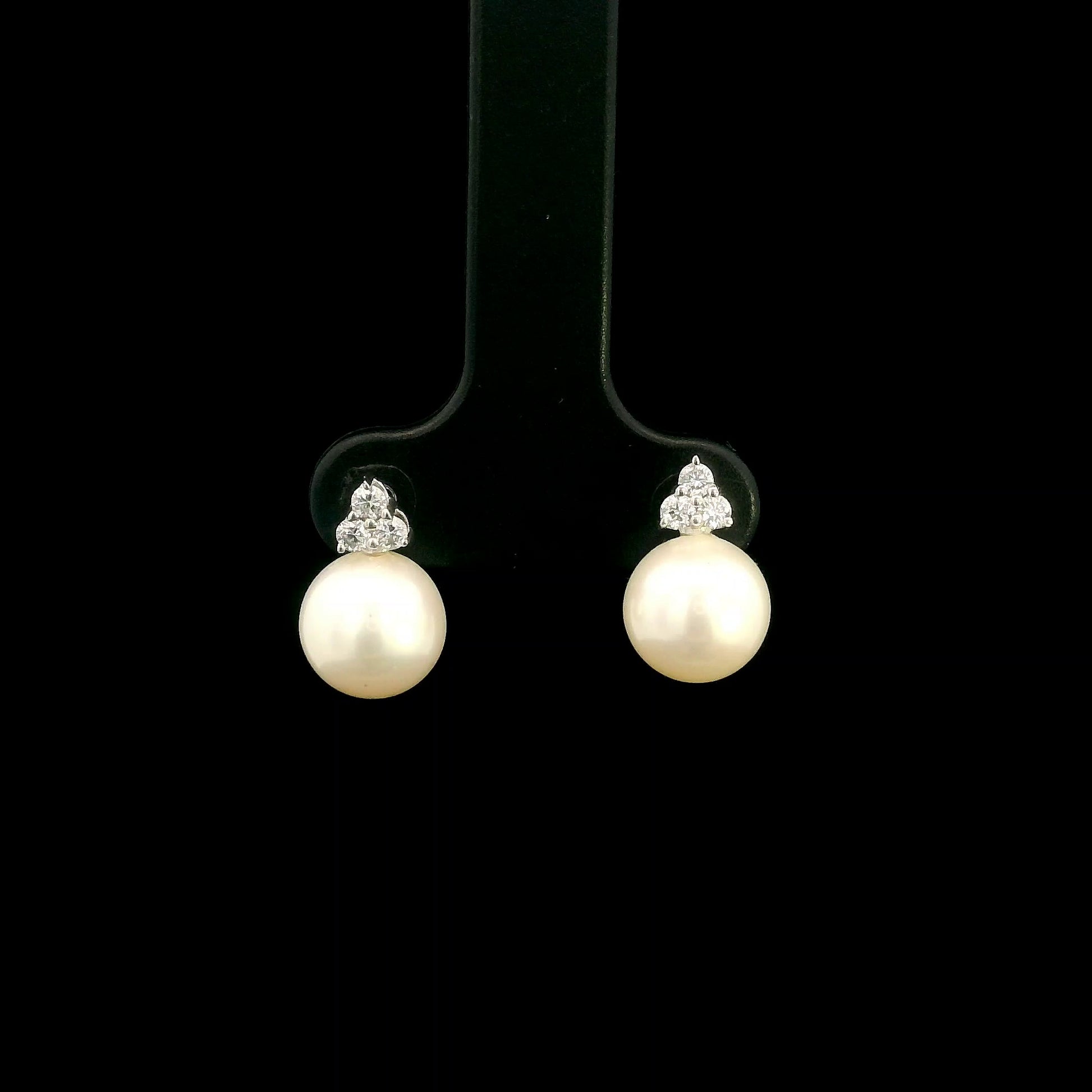 18K white gold freshwater pearl stud earrings featuring 7.5 × 8 mm freshwater pearls with a natural round diamond three-stone cluster and secure butterfly backs.