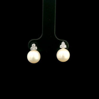 18K white gold freshwater pearl stud earrings featuring 7.5 × 8 mm freshwater pearls with a natural round diamond three-stone cluster and secure butterfly backs.