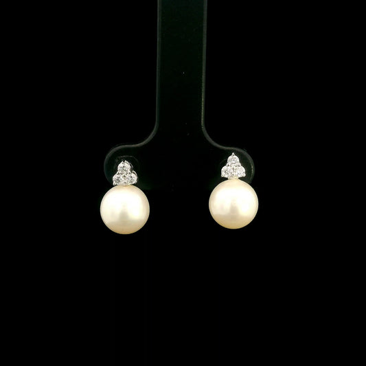 18K white gold freshwater pearl stud earrings featuring 7.5 × 8 mm freshwater pearls with a natural round diamond three-stone cluster and secure butterfly backs.