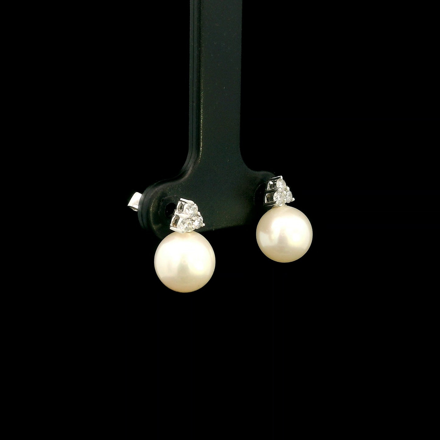 18K white gold freshwater pearl stud earrings featuring 7.5 × 8 mm freshwater pearls with a natural round diamond three-stone cluster and secure butterfly backs.