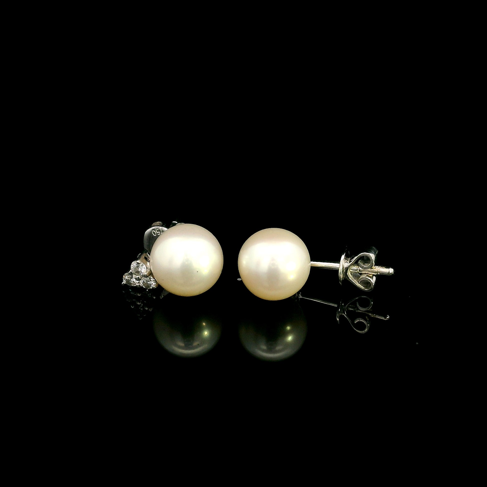 18K white gold freshwater pearl stud earrings featuring 7.5 × 8 mm freshwater pearls with a natural round diamond three-stone cluster and secure butterfly backs.