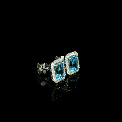 Blue Topaz diamond halo stud earrings in 18K white gold featuring 2.36 carats of natural emerald-cut Blue Topaz and 0.32 carat natural diamonds.