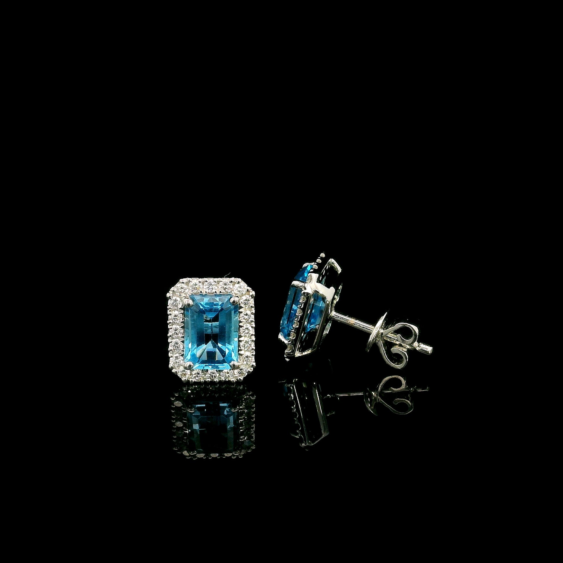 Blue Topaz diamond halo stud earrings in 18K white gold featuring 2.36 carats of natural emerald-cut Blue Topaz and 0.32 carat natural diamonds.