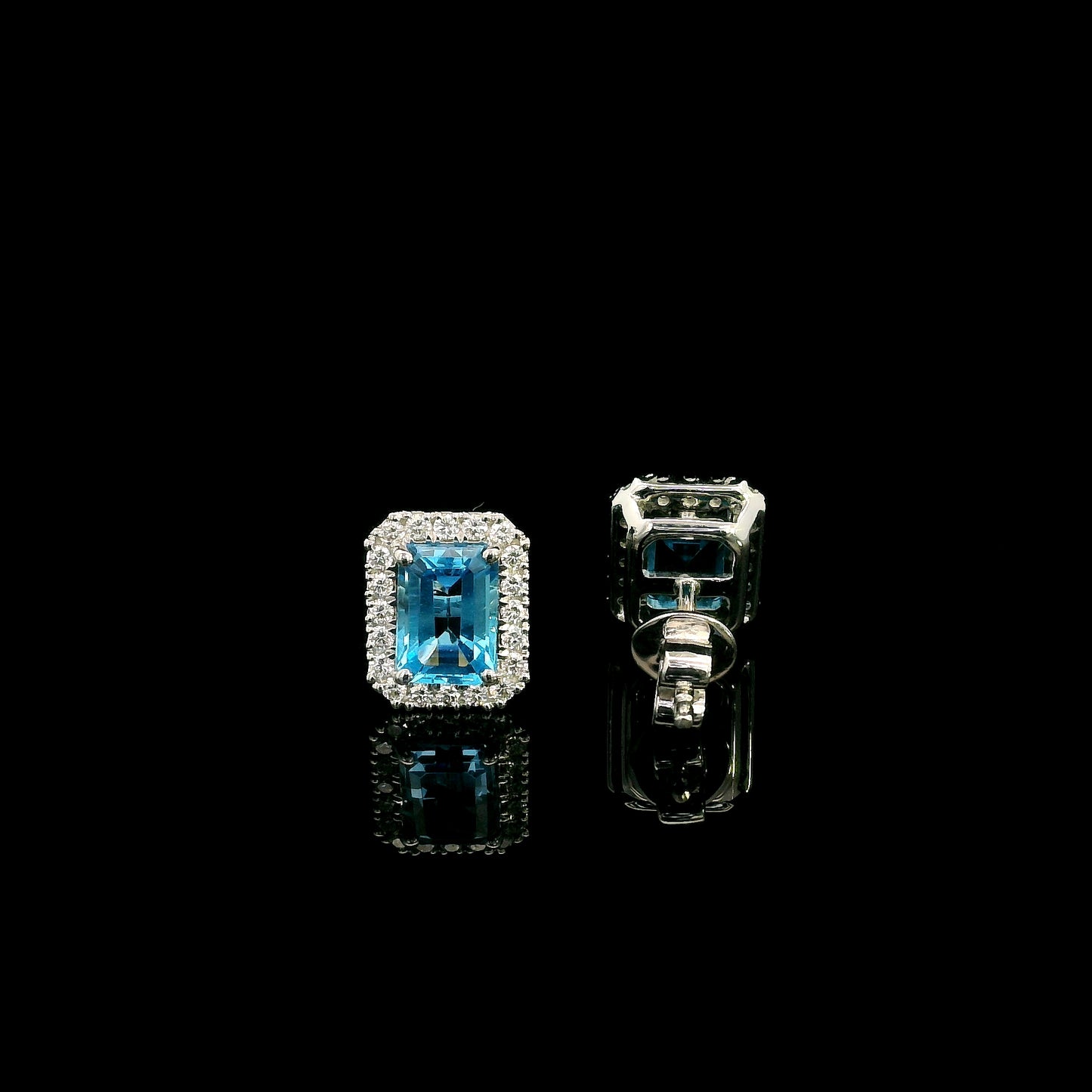 Blue Topaz diamond halo stud earrings in 18K white gold featuring 2.36 carats of natural emerald-cut Blue Topaz and 0.32 carat natural diamonds.