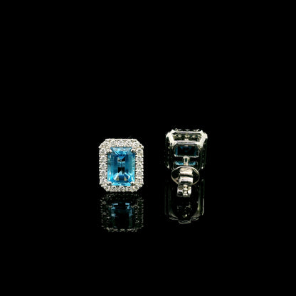 Blue Topaz diamond halo stud earrings in 18K white gold featuring 2.36 carats of natural emerald-cut Blue Topaz and 0.32 carat natural diamonds.