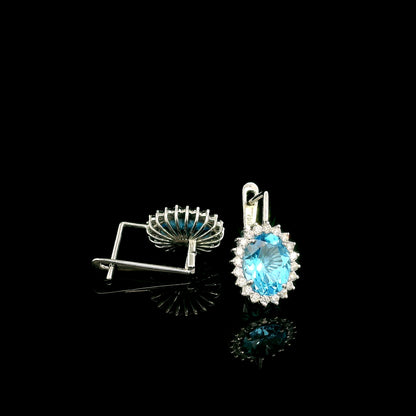 Oval Swiss Blue Topaz drop earrings with diamond halos in 18K white gold