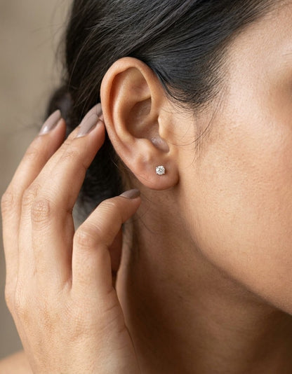 Diamond solitaire stud earrings in 18K white gold featuring round brilliant diamonds in classic four-prong settings.