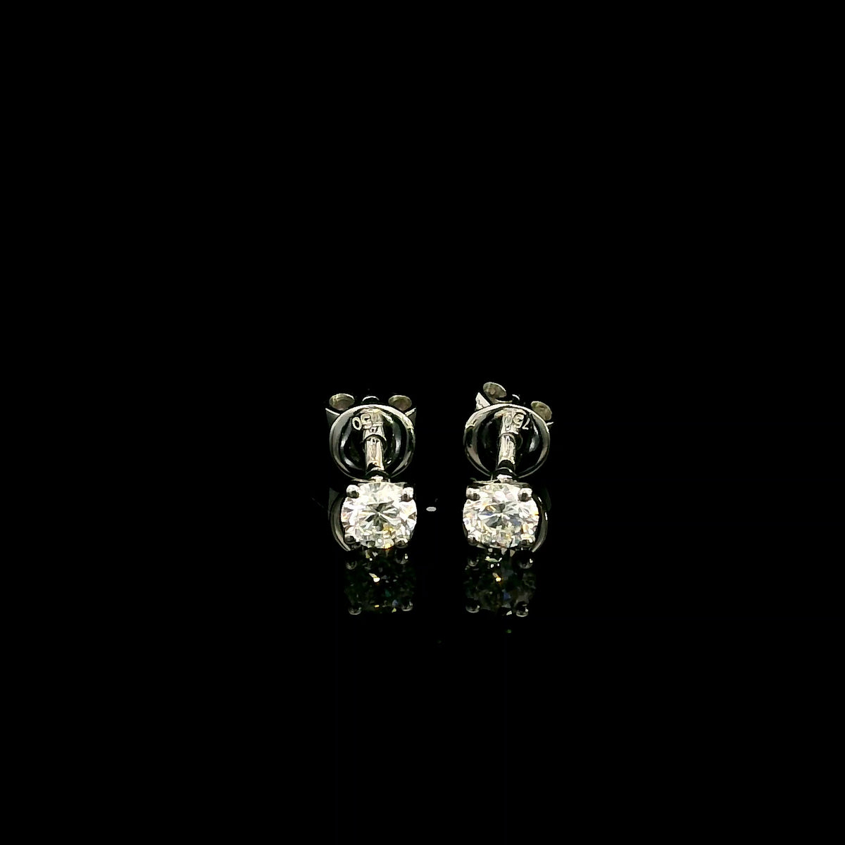 Diamond solitaire stud earrings in 18K white gold featuring round brilliant diamonds in classic four-prong settings.