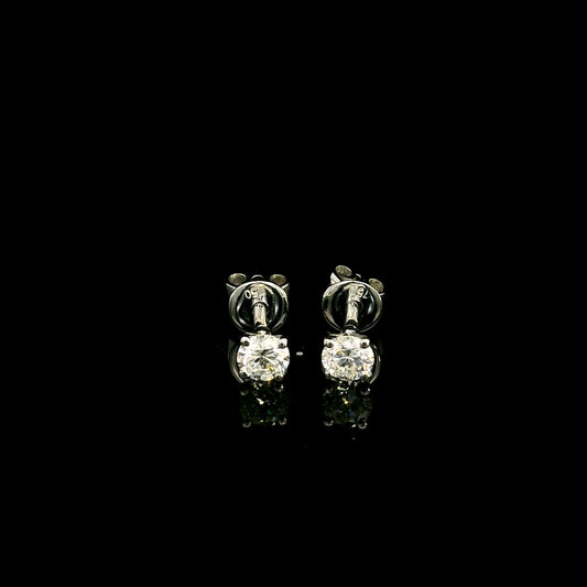 Diamond solitaire stud earrings in 18K white gold featuring round brilliant diamonds in classic four-prong settings.
