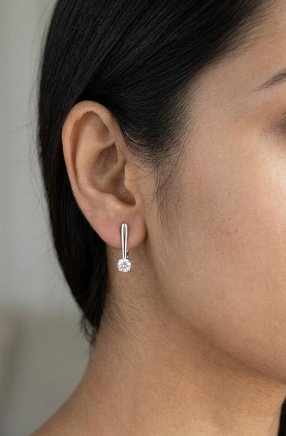 Round brilliant diamond drop earrings in 18K white gold featuring single four-prong set diamonds suspended beneath polished gold details.