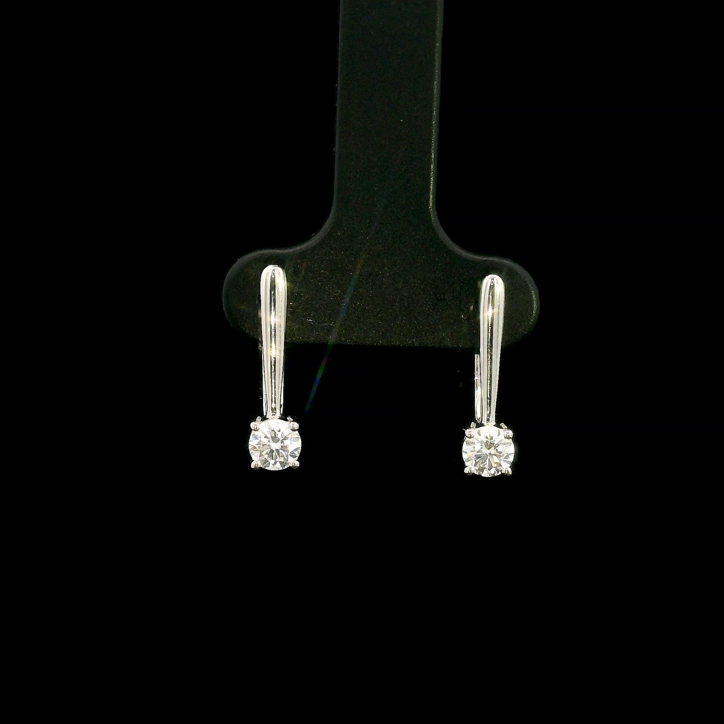 Round brilliant diamond drop earrings in 18K white gold featuring single four-prong set diamonds suspended beneath polished gold details.