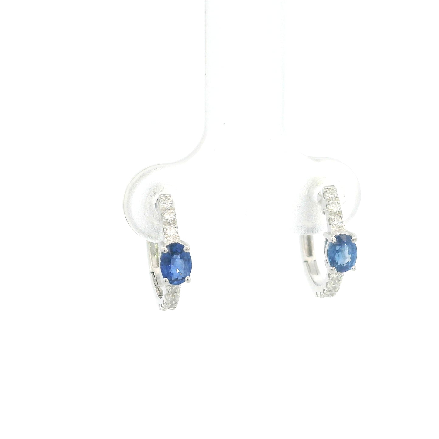 18K white gold blue sapphire and diamond huggie hoop earrings featuring oval blue sapphires and diamond-set hoops.