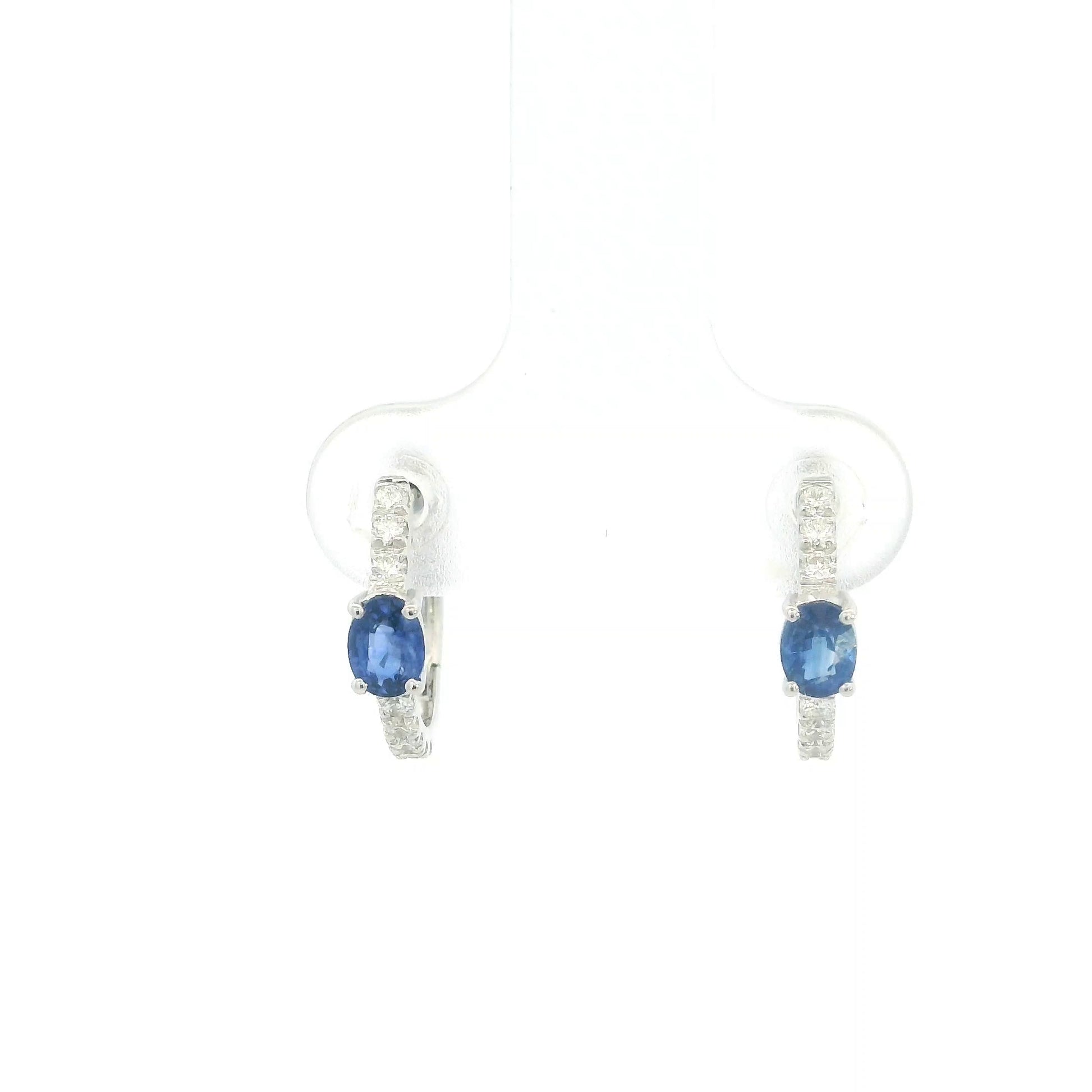18K white gold blue sapphire and diamond huggie hoop earrings featuring oval blue sapphires and diamond-set hoops.