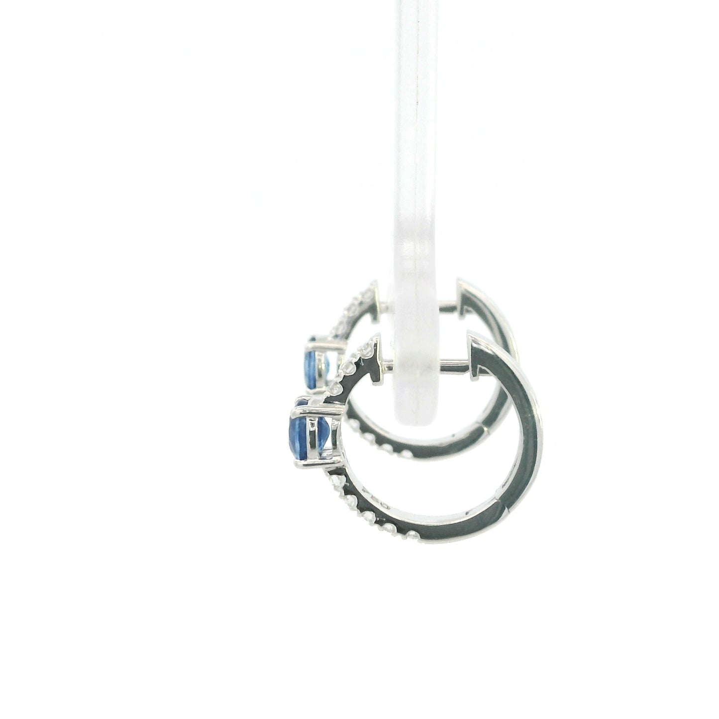 18K white gold blue sapphire and diamond huggie hoop earrings featuring oval blue sapphires and diamond-set hoops.
