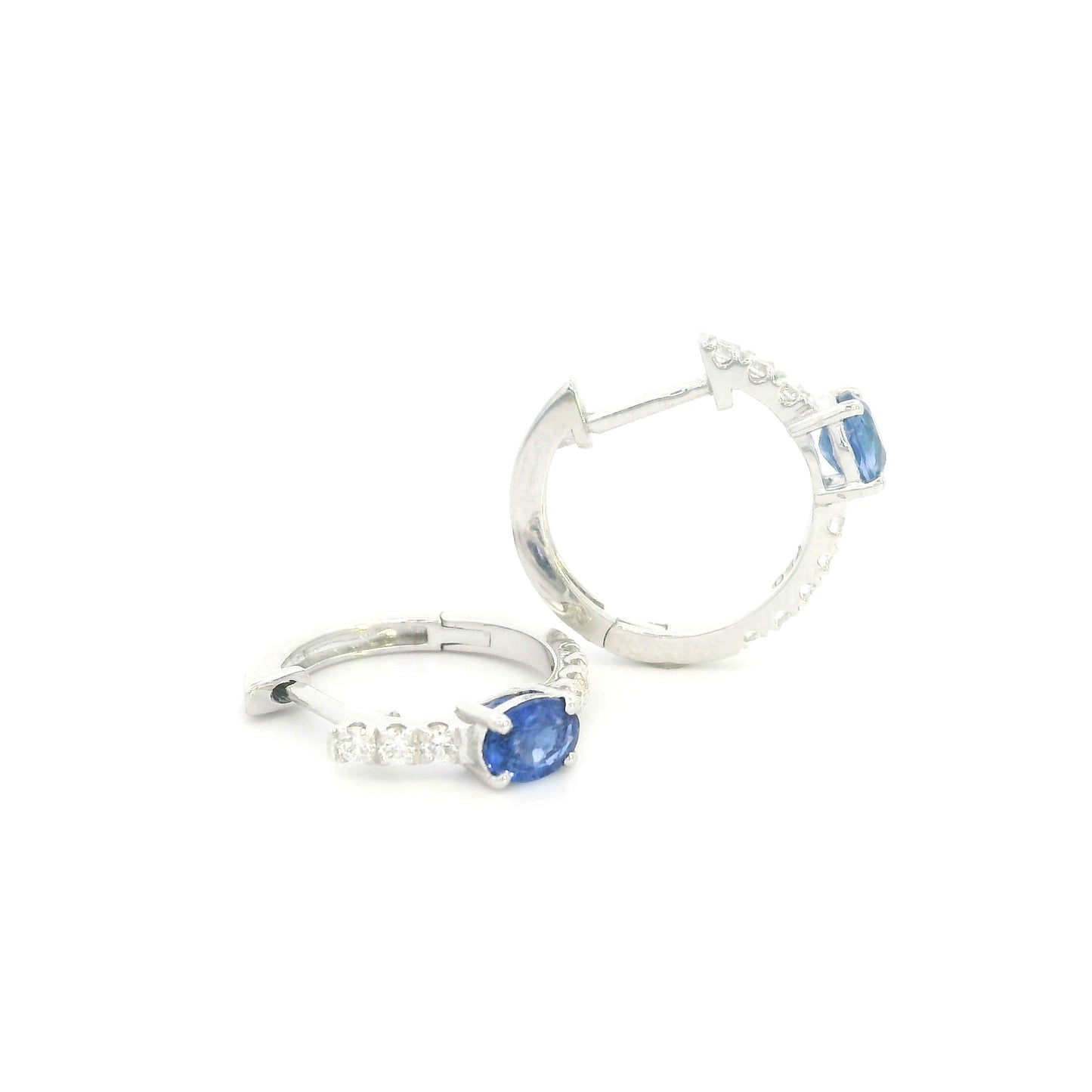 18K white gold blue sapphire and diamond huggie hoop earrings featuring oval blue sapphires and diamond-set hoops.