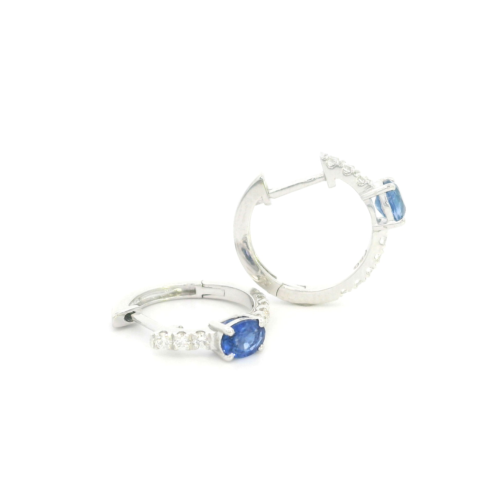 18K white gold blue sapphire and diamond huggie hoop earrings featuring oval blue sapphires and diamond-set hoops.
