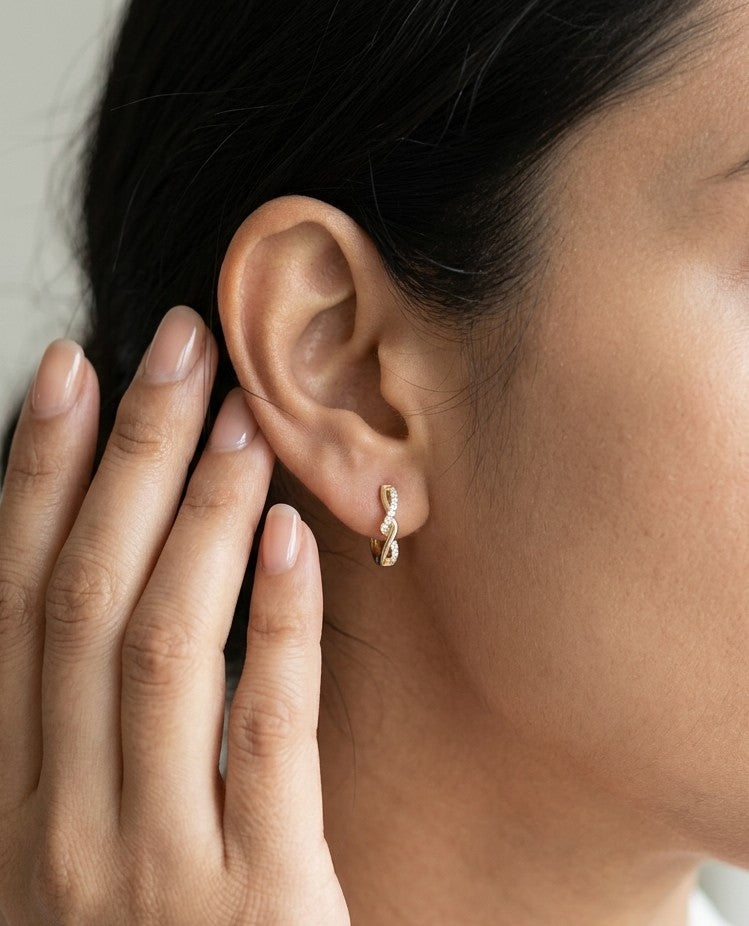 Diamond twist hoop earrings in 18K yellow gold with intertwined polished gold and round brilliant diamond details.