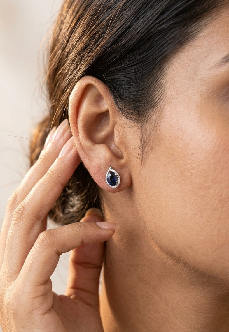 Oval blue sapphire and diamond stud earrings in 18K white gold with curved diamond accents