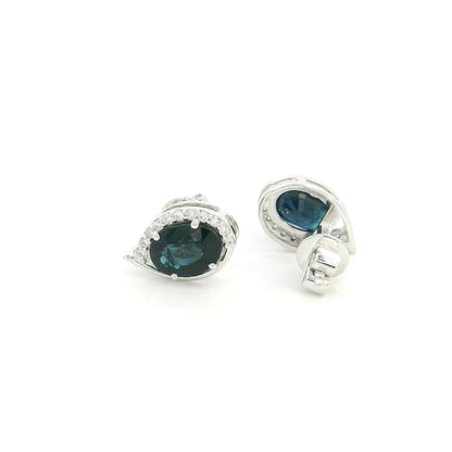 Oval blue sapphire and diamond stud earrings in 18K white gold with curved diamond accents
