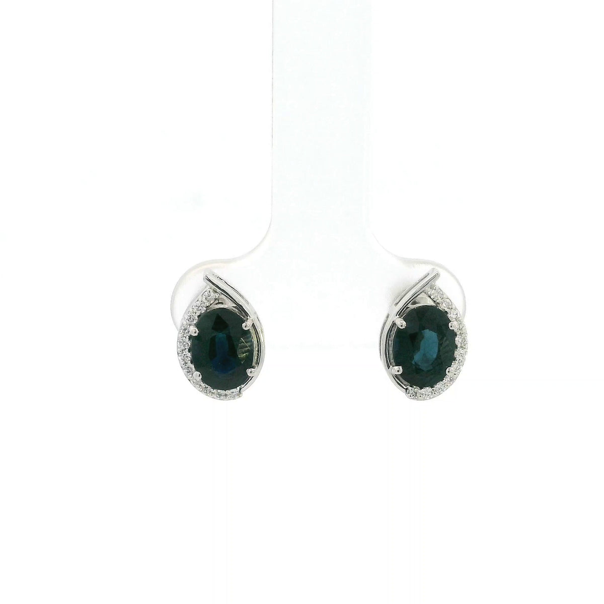 Oval blue sapphire and diamond stud earrings in 18K white gold with curved diamond accents