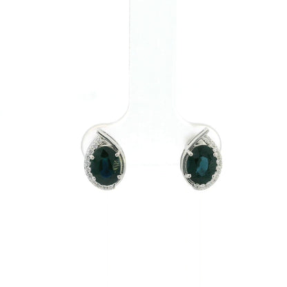 Oval blue sapphire and diamond stud earrings in 18K white gold with curved diamond accents