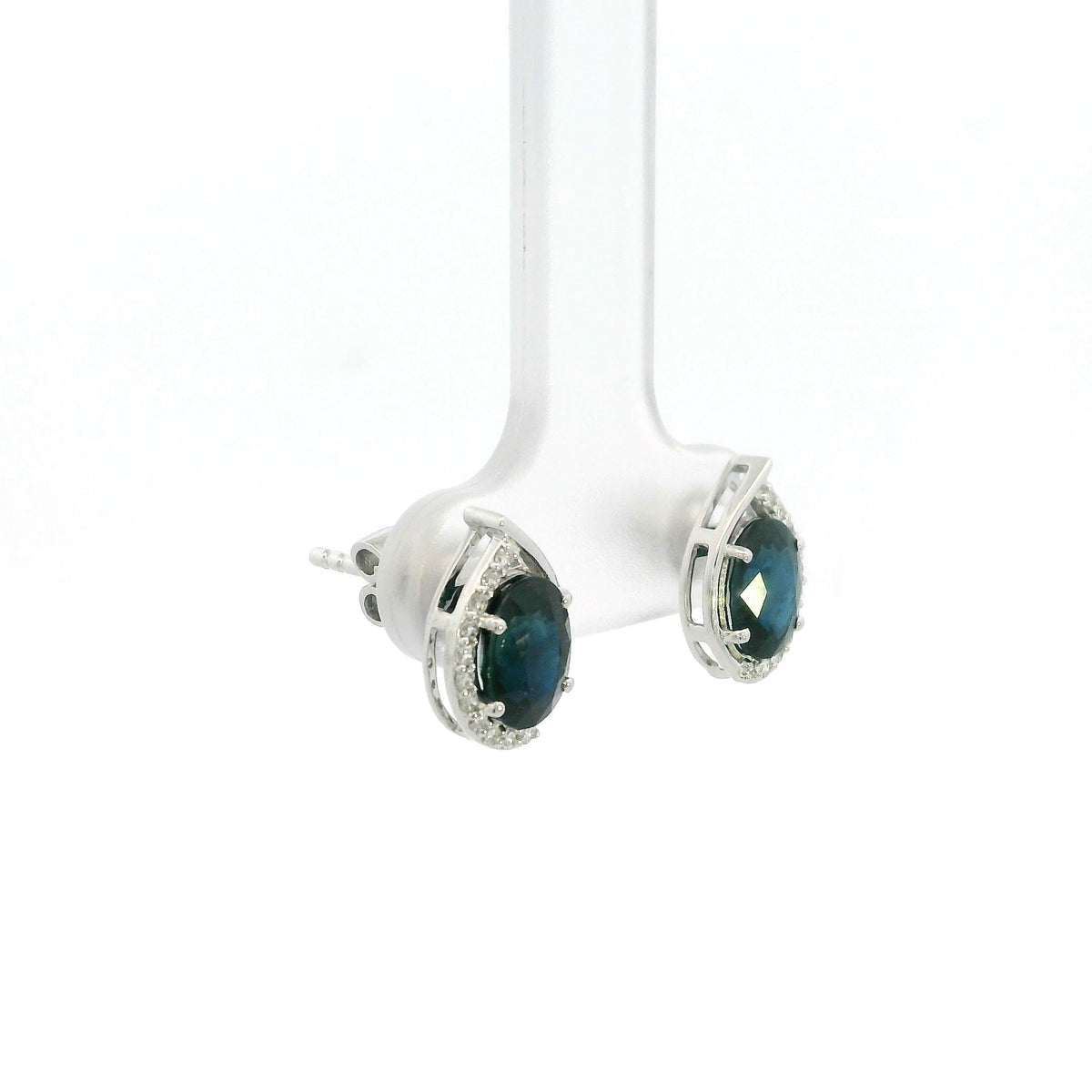 Oval blue sapphire and diamond stud earrings in 18K white gold with curved diamond accents