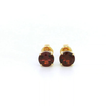 Round garnet solitaire stud earrings in 18K yellow gold with classic four-prong settings by Emirates Diamonds.