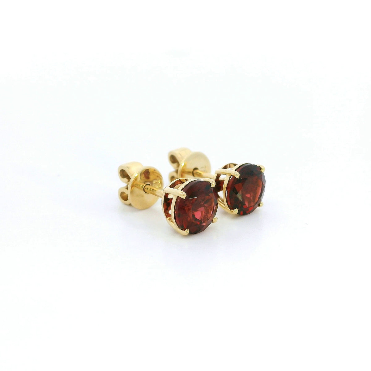 Round garnet solitaire stud earrings in 18K yellow gold with classic four-prong settings by Emirates Diamonds.