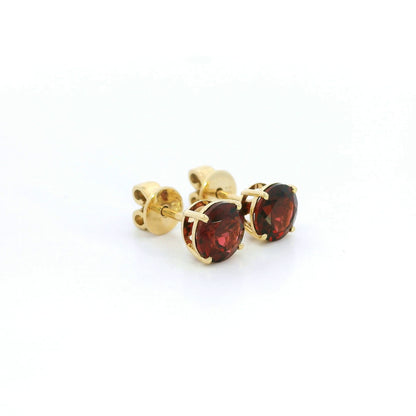 Round garnet solitaire stud earrings in 18K yellow gold with classic four-prong settings by Emirates Diamonds.