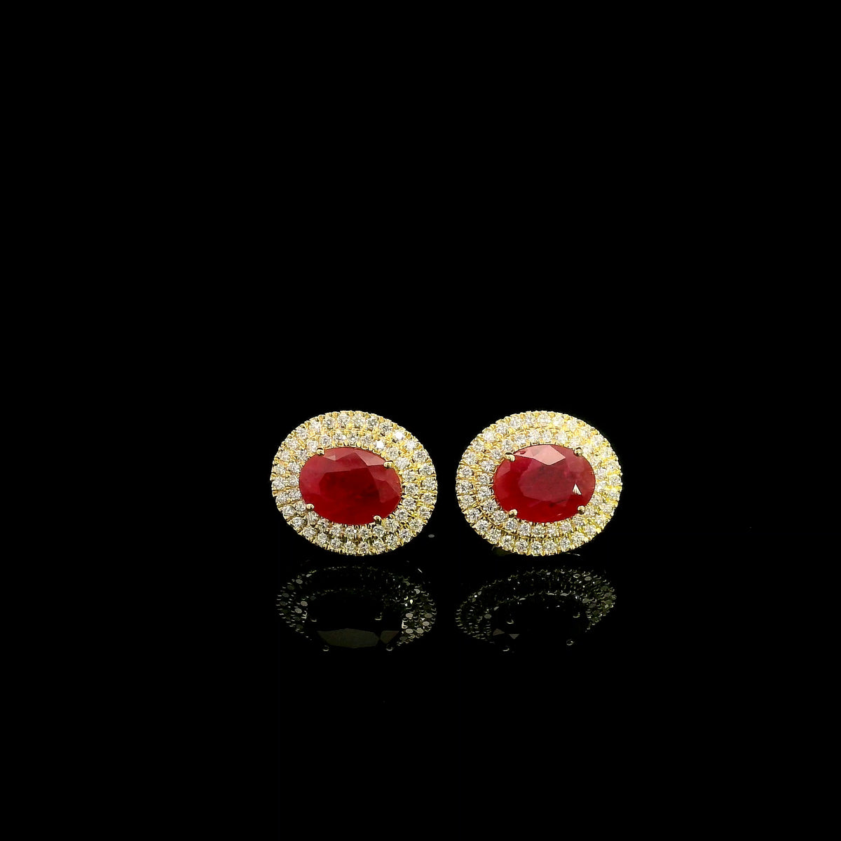 Oval ruby and double diamond halo stud earrings in 18K yellow gold by Emirates Diamonds.