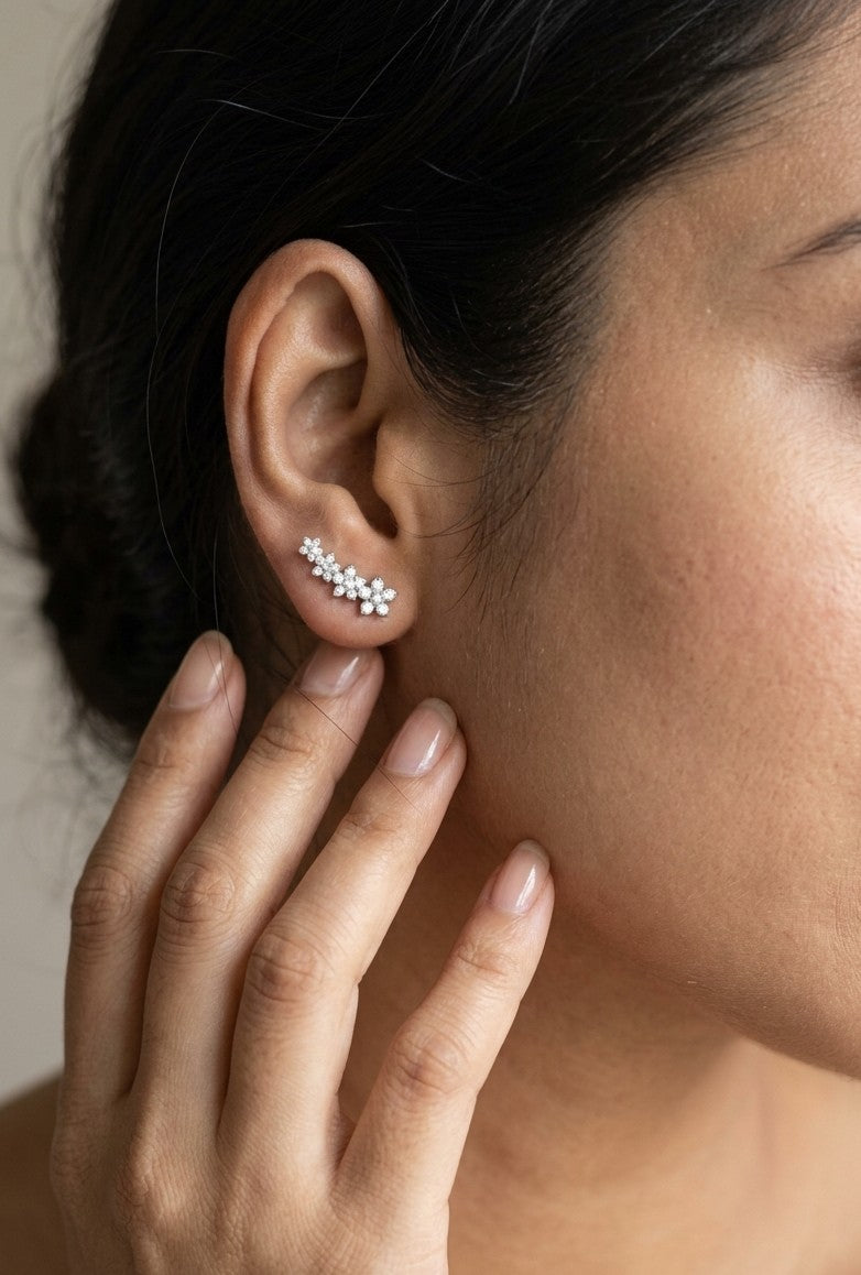 Diamond floral ear climber earrings in 18K white gold with graduating round diamond flower clusters designed to follow the ear.