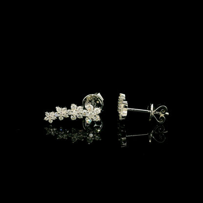 Diamond floral ear climber earrings in 18K white gold with graduating round diamond flower clusters designed to follow the ear.